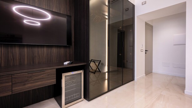 Un intérieur moderne avec un mur lambrissé en bois foncé, un téléviseur à écran plat, une cloison en verre et un design minimaliste.