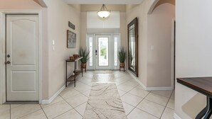 A hallway with a white door, a light fixture, a rug, and a framed picture on the wall. - Poolside Bliss/fenced yard/water views/golf/pickleball/pets/tennis/sun & fun (Laguna Vista)