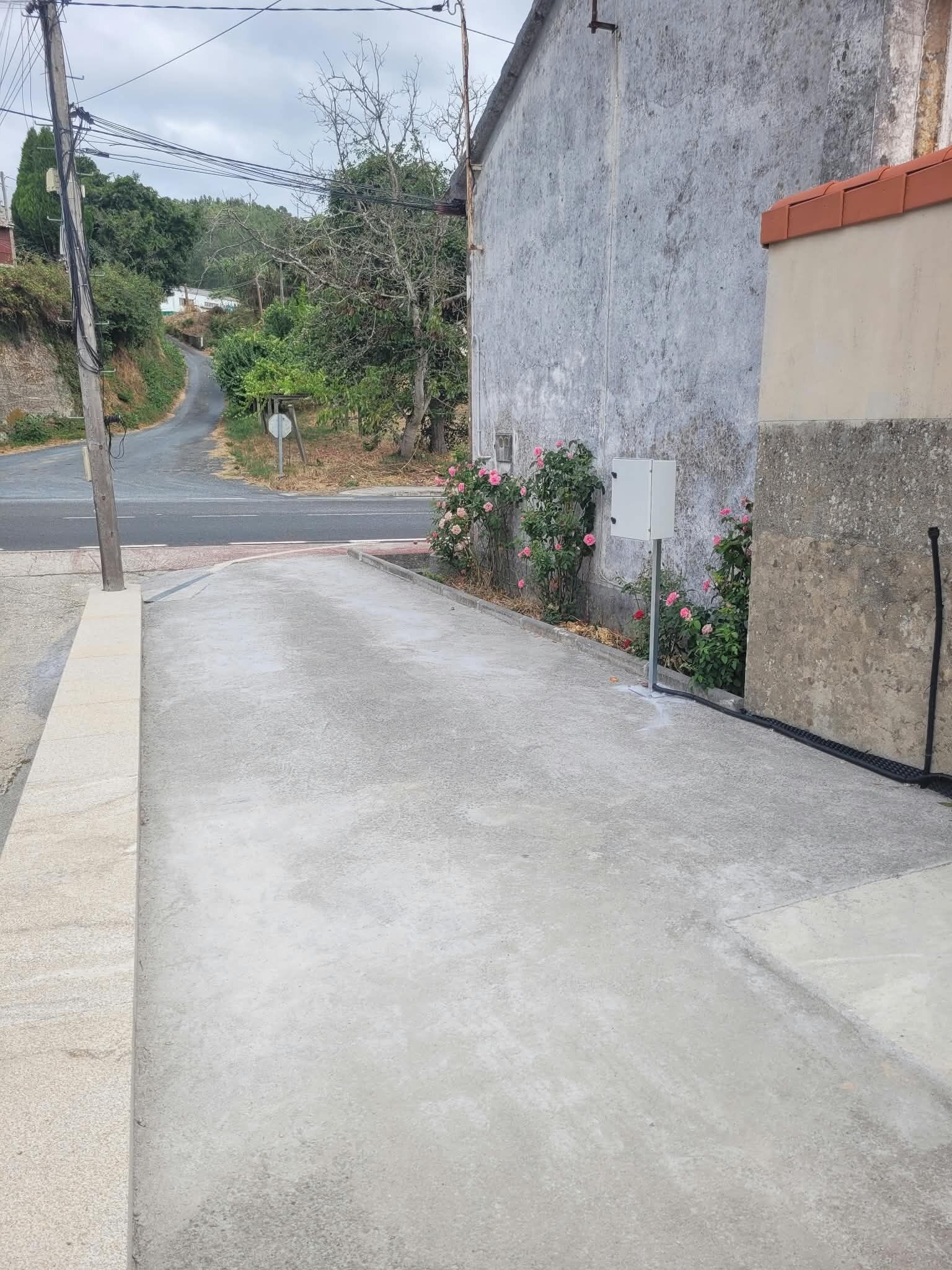 Uma calçada de concreto leva a um edifício com telhado de telhas vermelhas, um poste de eletricidade e uma placa de pare.