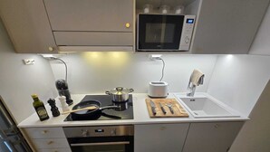 A compact kitchen with a built-in oven, a microwave, a toaster, and a sink. - Viherpihan helmi | Free parking & Netflix | 5G | 100 m to metro (Espoo)