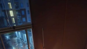 A balcony with a cushioned seating area, a small table with a lantern, and a view of a street at night. - Viherpihan helmi | Free parking & Netflix | 5G | 100 m to metro (Espoo)