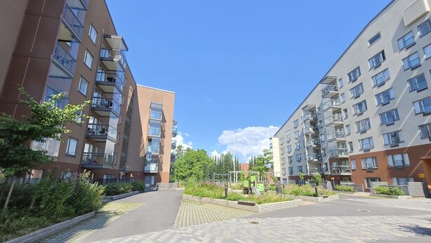 A modern apartment complex with multiple floors, balconies, and a paved walkway. - Viherpihan helmi | Free parking & Netflix | 5G | 100 m to metro (Espoo)