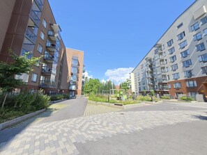 Un immeuble d’appartements moderne, doté de plusieurs étages, de balcons et d’une allée piétonne dallée.