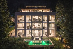 Un hotel de varios pisos con balcones, piscina y fachada bien iluminada.