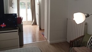 A living room with a television, a radiator, and a sofa. - Cosy Vallée Studio (Pau)