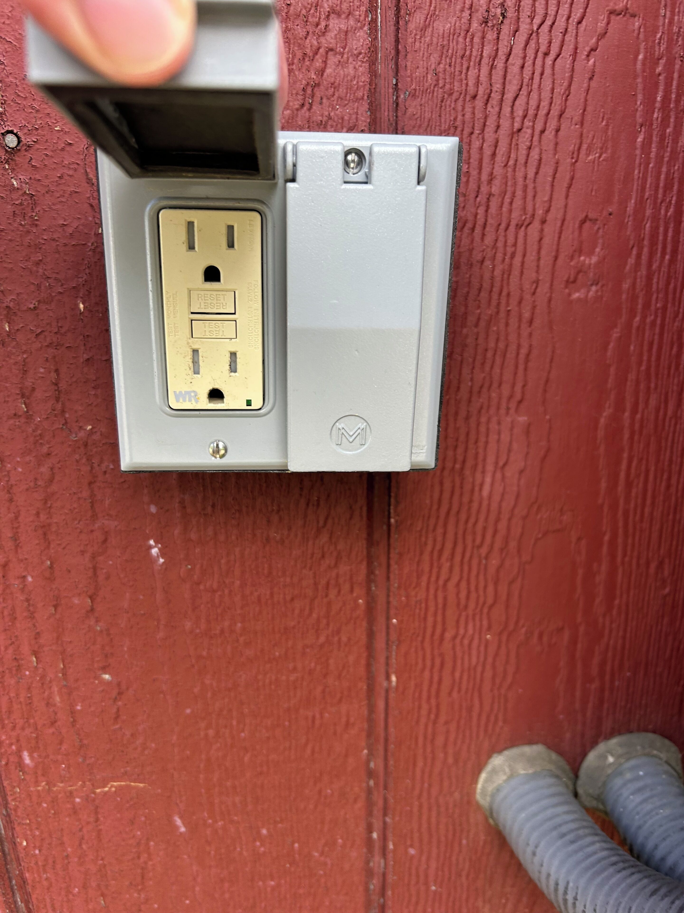 A wall-mounted electrical outlet with a visible reset and test button, and a visible brand logo.