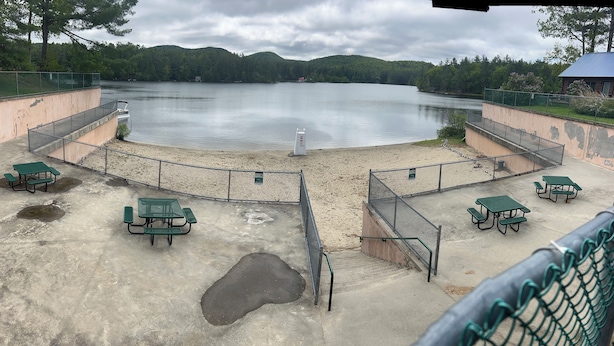 A lakeside park with picnic tables and a concrete walkway.