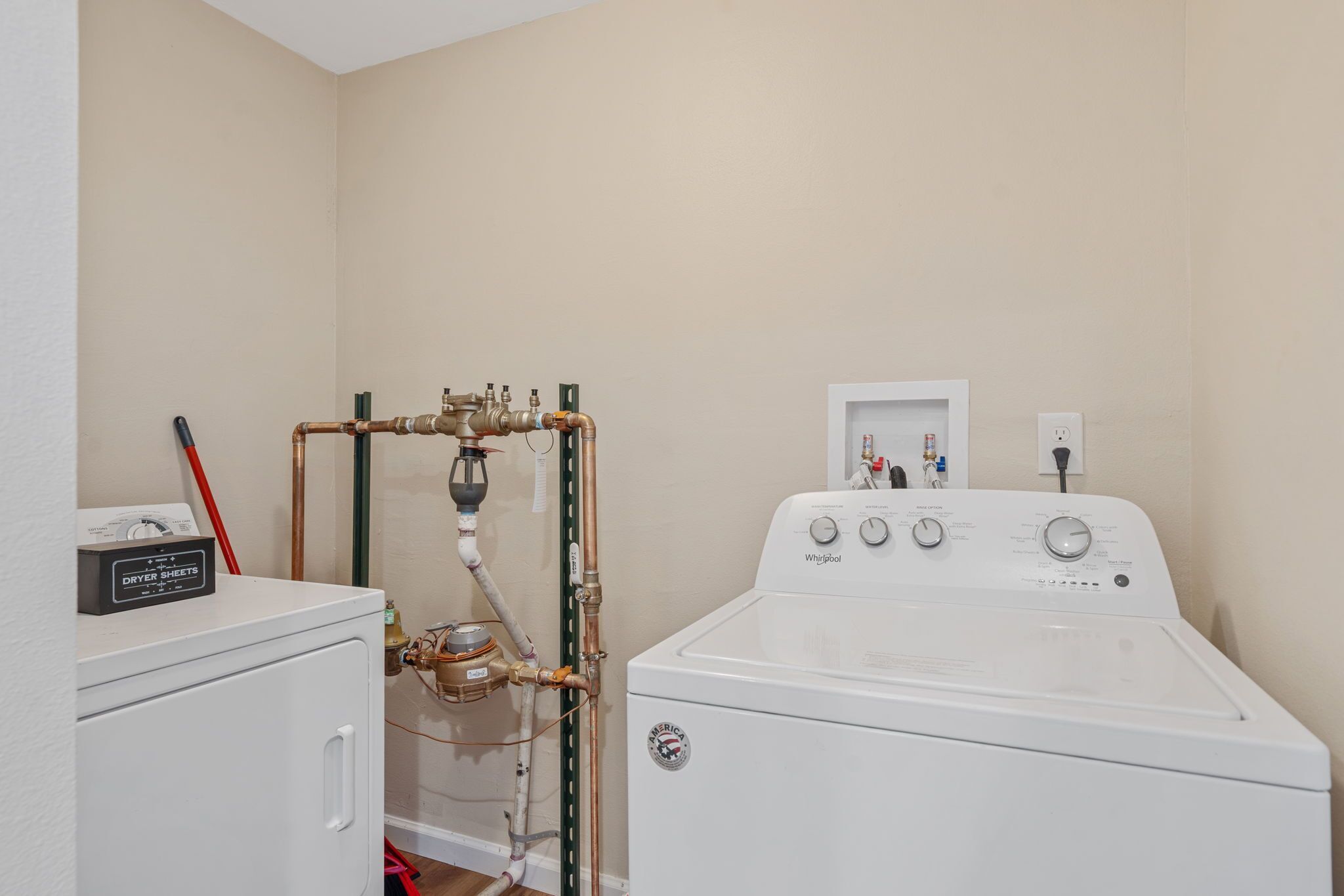 A laundry room with a washer and dryer, a water heater, and a control panel.
