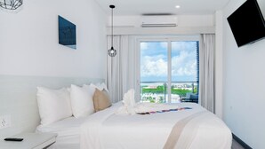 Ein modernes Hotelzimmer mit einem großen Bett, einem Flachbildfernseher und einem Balkon mit Blick auf die Stadt.