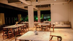 Un restaurante con mesas y sillas de madera, un sofá y vistas al exterior.