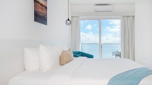 Un cuarto de hotel con una cama grande, vista al mar y un balcón.