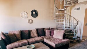 A living room with a sectional sofa, a coffee table, and a spiral staircase. - Home Away from Home in Mesa (Mesa)