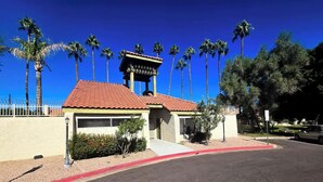 A small building with a red-tiled roof and a white facade, surrounded by palm trees and a clear blue sky. - Home Away from Home in Mesa (Mesa)