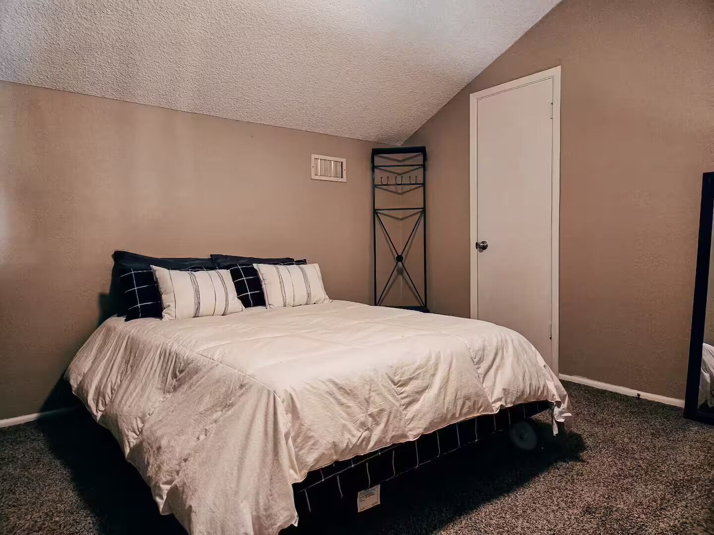A bedroom with a bed, a door, and a wall-mounted shelf.