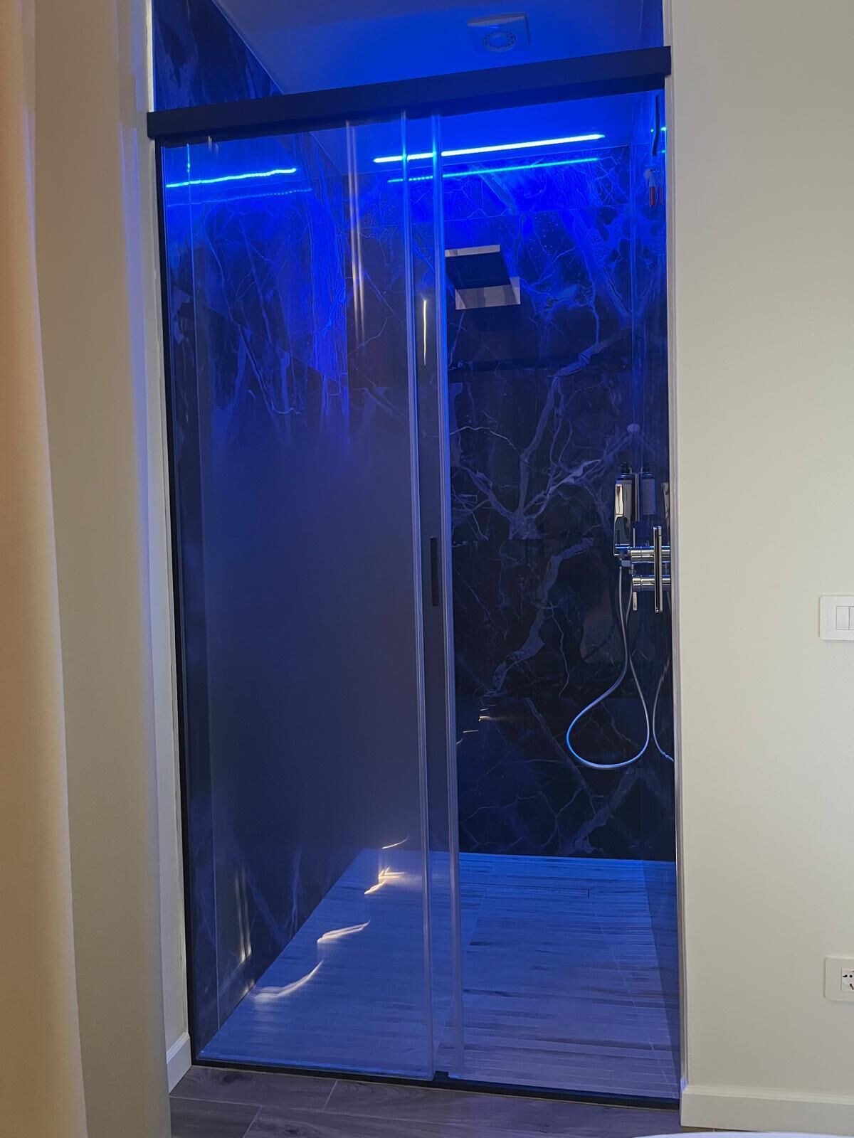 Un ascensor moderno con puerta de vidrio e iluminación azul.