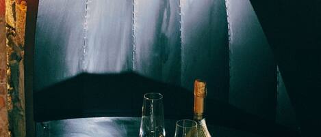 A table with a glass dome-shaped seating area, a bottle of champagne, and two glasses.