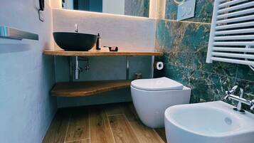 Ein modernes Badezimmer mit einem Holzkosmetikschrank, einem großzügigen Waschbecken und zwei Bidet-Einheiten.