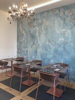 Un comedor con paredes de mármol, sillas de cobre y una lámpara de araña.