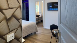 A modern hotel room with a bed, a desk, and a TV mounted on the wall. - ARICCIA LUXURY HOUSE (Ariccia)