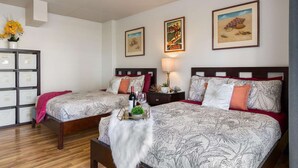 A hotel room with two beds, a nightstand with a lamp, a small table with a wine bottle, and a decorative plant. - 4th Fl Ilikai | Pool | AC | Marina View (Honolulu)