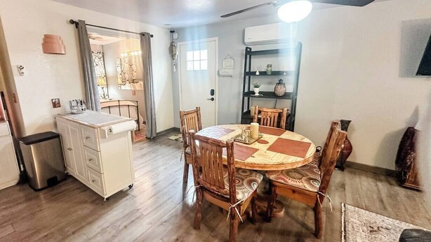 A dining area with a round table, wooden chairs, and a ceiling fan.