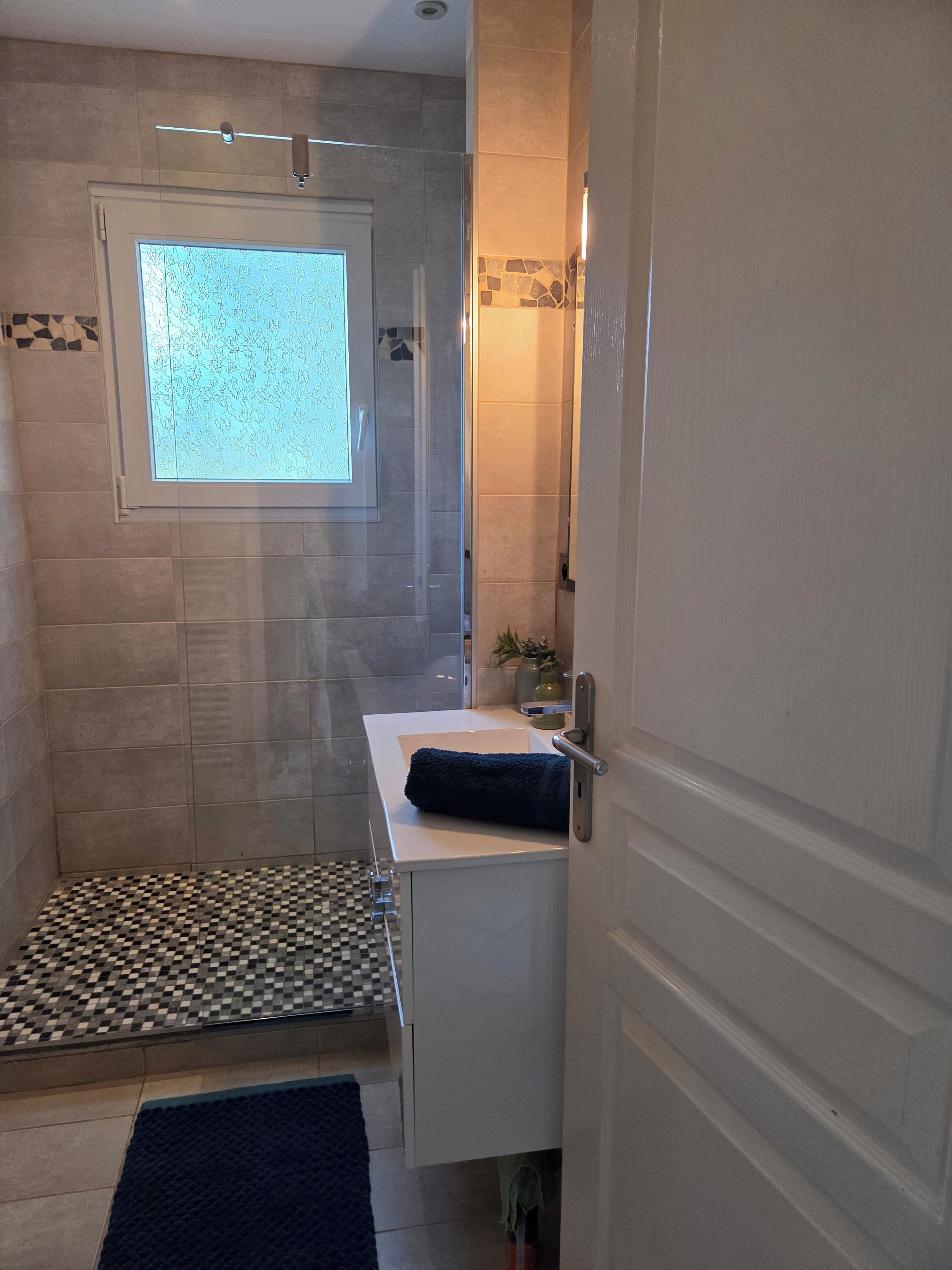 Un baño con ducha, lavamanos y ventana.