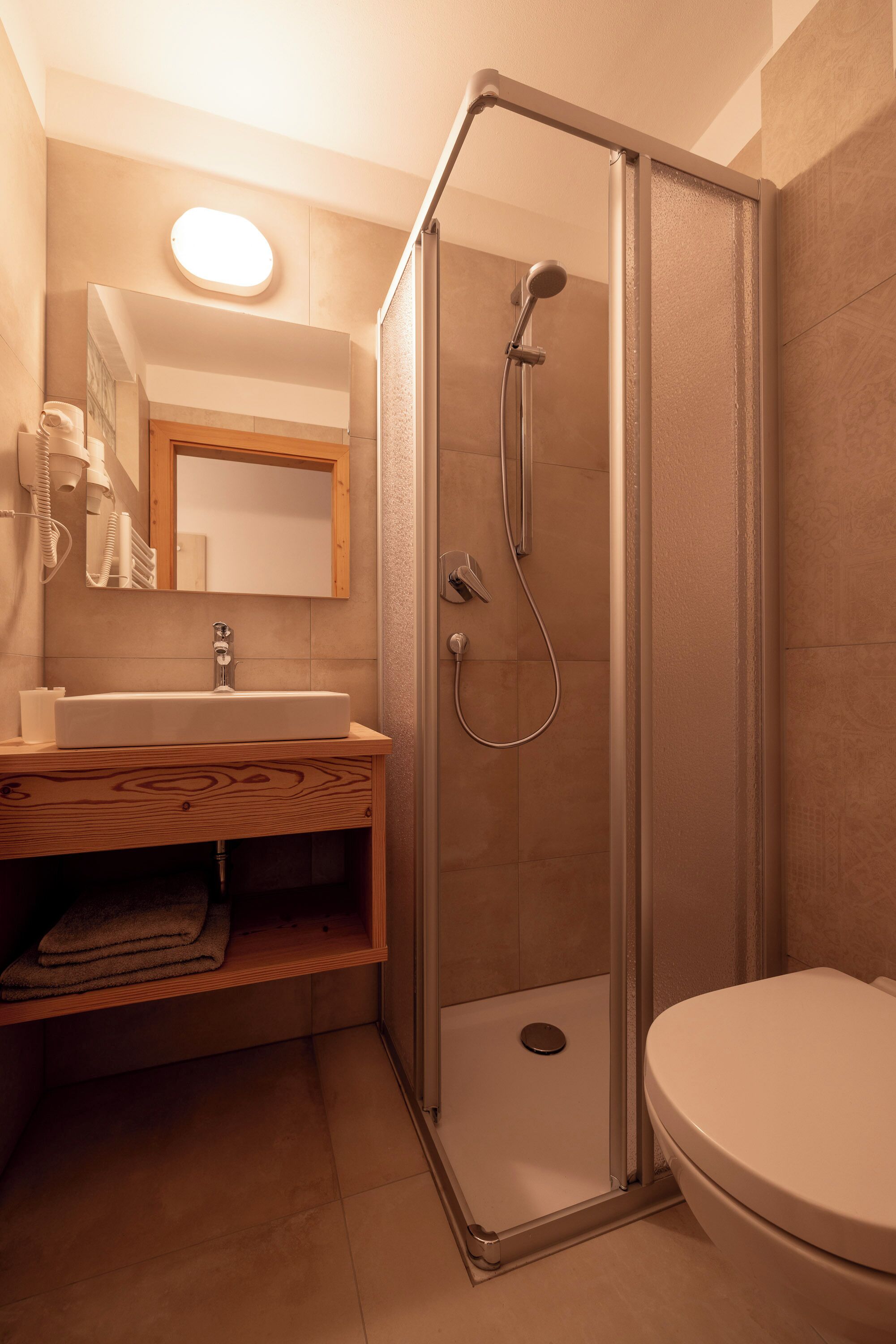 Un baño con ducha, inodoro, lavamanos y espejo.