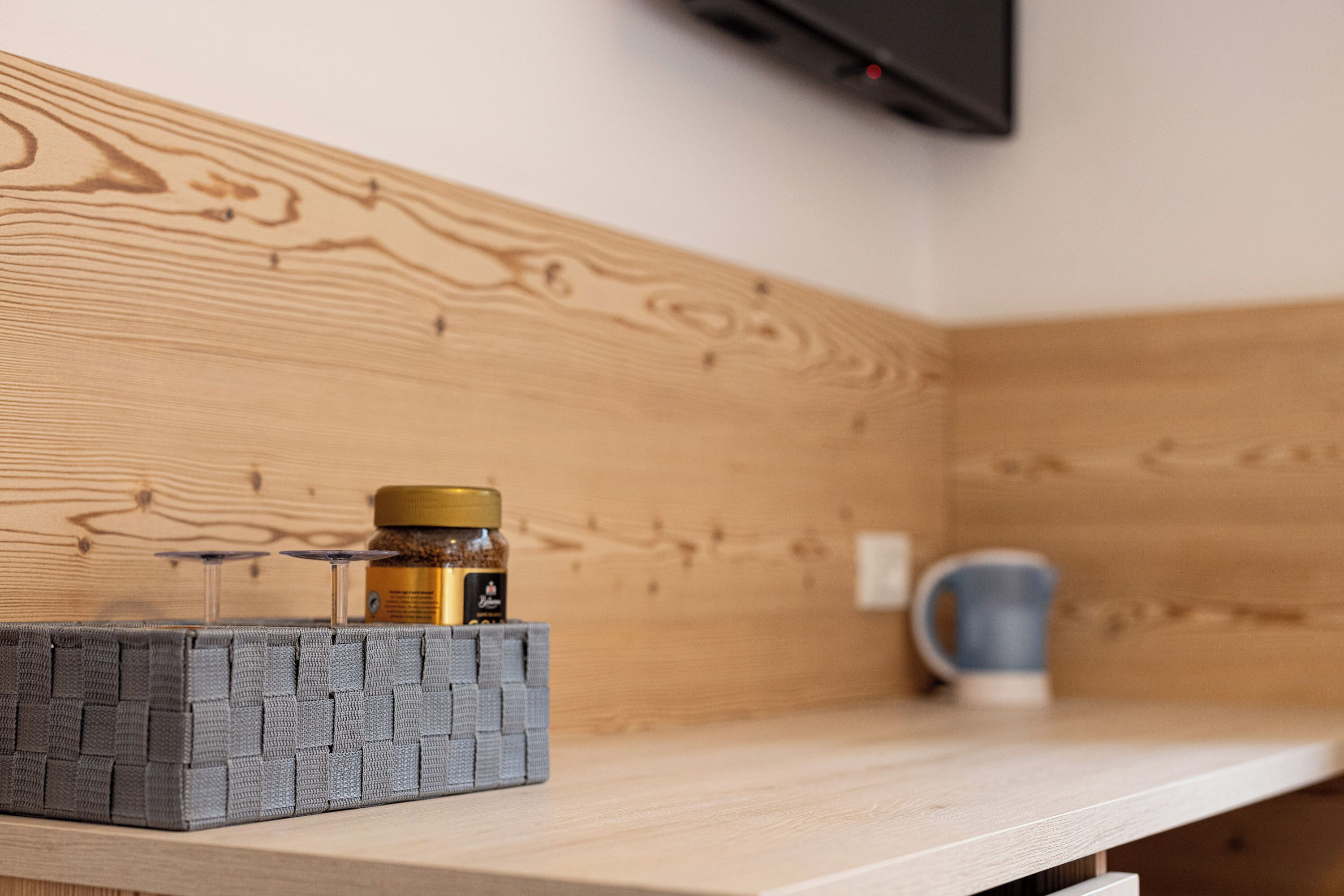 Una pared de madera con un estante que sostiene un tarro y un vaso.