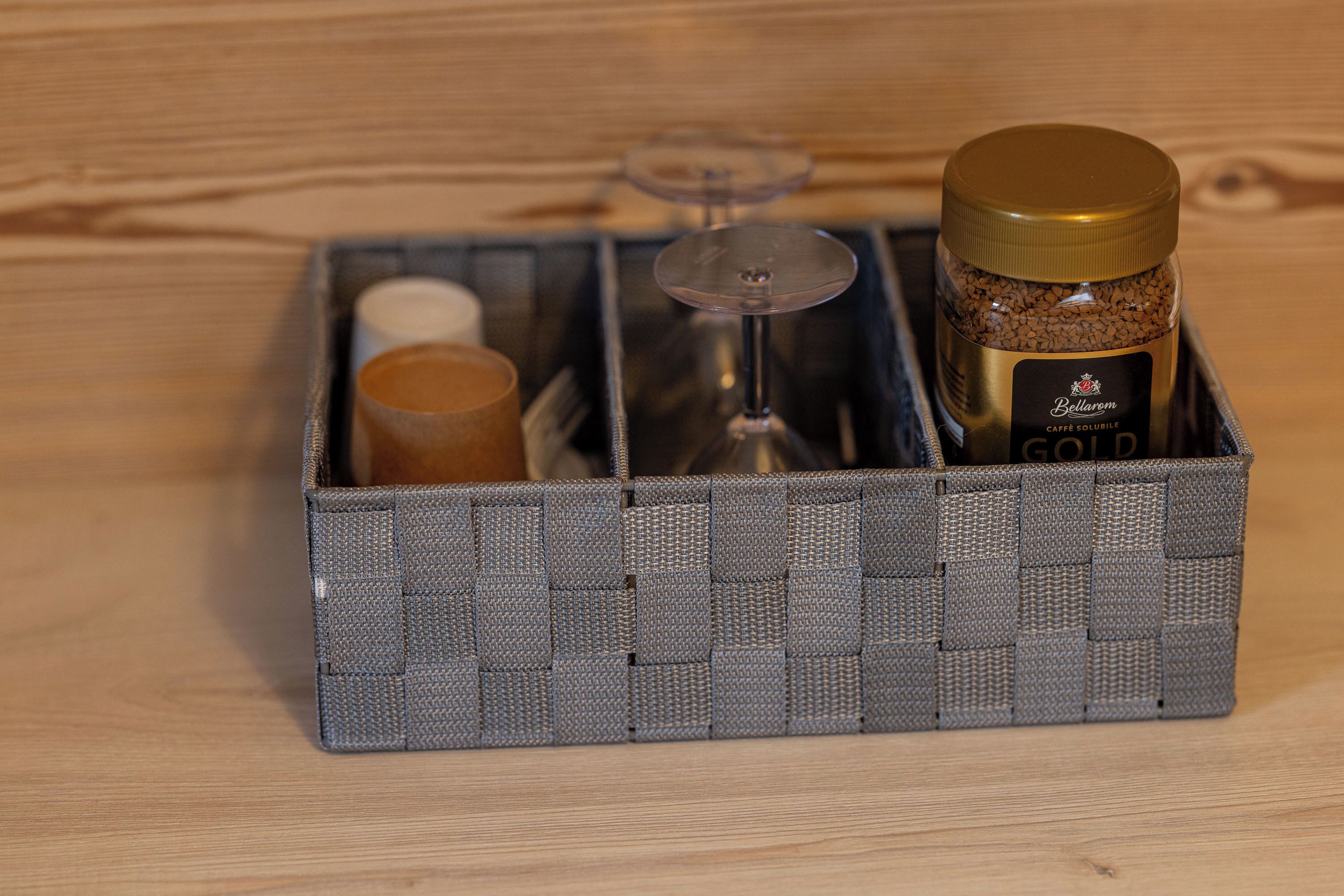 Une boîte de rangement contenant un bocal étiqueté « Bellareum », un récipient en verre et un objet cylindrique de couleur marron.