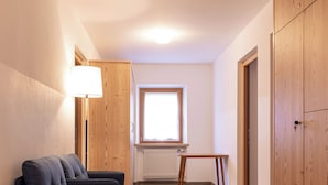 Un corridoio stretto con un divano blu scuro, un armadio in legno e un tavolino.