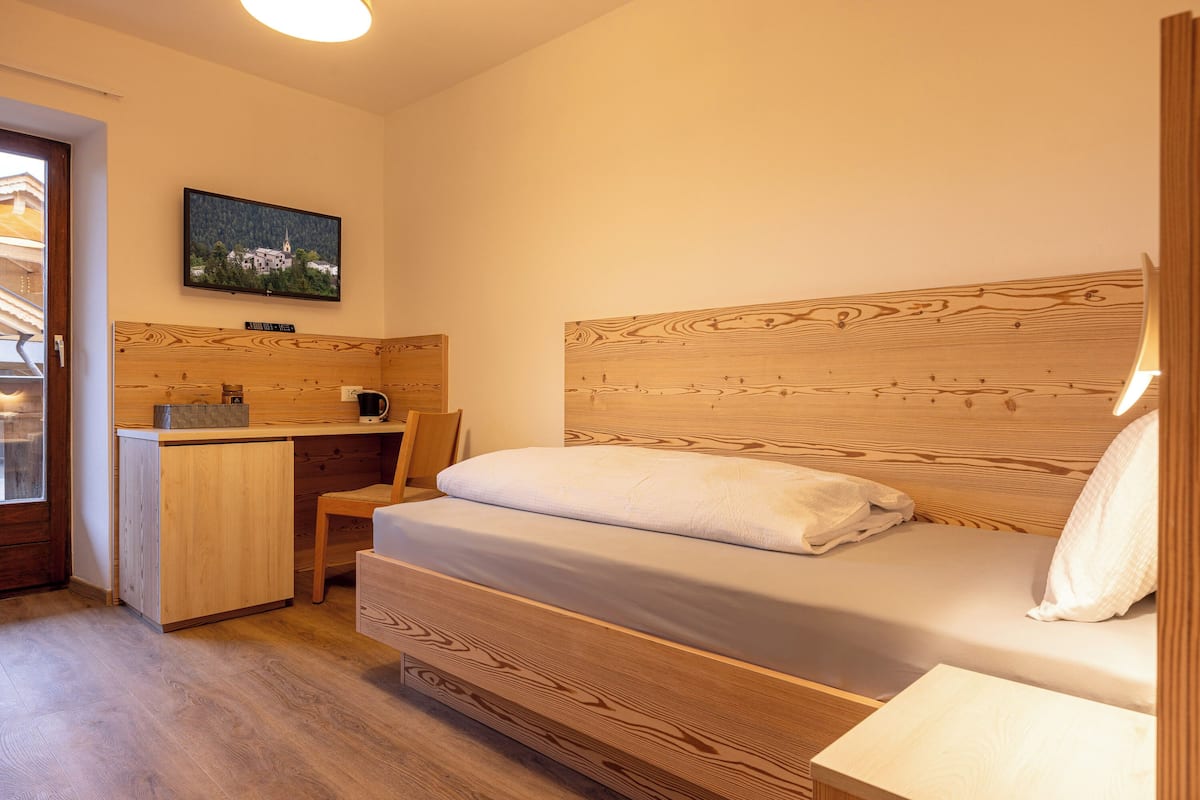 A bedroom with a wooden bed, a desk, and a chair.
