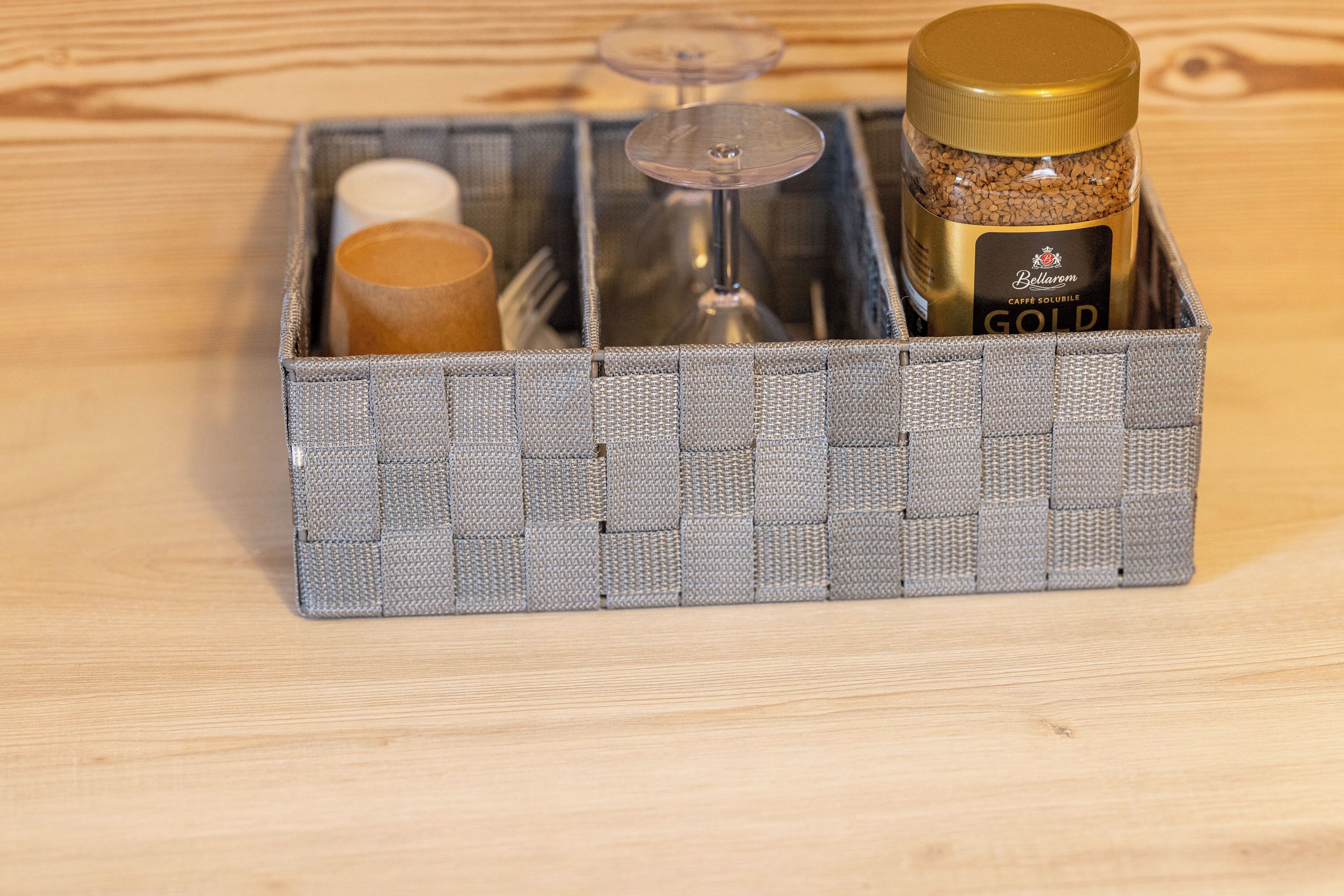 A storage box containing a bottle labeled 'Bellarmere Gold', a wine glass, and a rolled-up item.