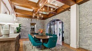 A dining area with a stone wall, wooden ceiling beams, and a chandelier. - First floor Cozy king room w/ Wine Country Charm (Santa Rosa)