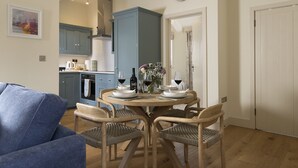 A dining area with a round table, four wicker chairs, and a clock on the wall. - The Stables at Sturt Farm Courtyard - Beautiful dog friendly home in the Cotswolds with a hot tub (Burford)