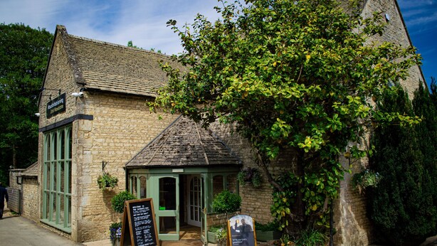 A stone building with a green door and windows, surrounded by greenery. - The Stables at Sturt Farm Courtyard - Beautiful dog friendly home in the Cotswolds with a hot tub (Burford)