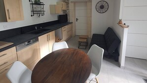 Eine moderne Küche mit Essbereich, ausgestattet mit einem Holztisch, weißen Stühlen und einem Einbauofen.