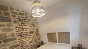 Ein Schlafzimmer mit Steinwand, einem Bett, einer Hängelampe und zwei Nachttischen.