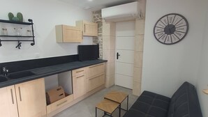Eine kleine Küche mit Holzausstattung, einer schwarzen Arbeitsplatte und einem schwarzen Sofa.