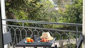 Een balkon met een tafel gedekt voor twee personen, met fruit en een hoed.