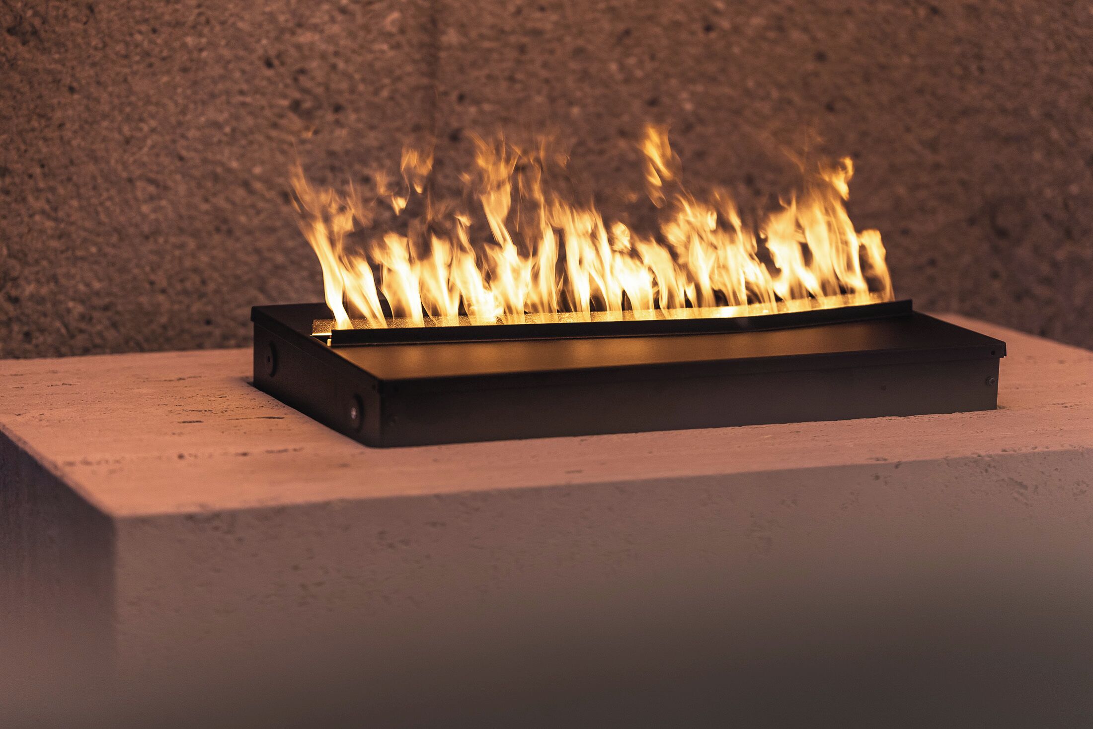 A rectangular metal fire feature with flames.