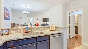 Cozinha moderna com bancadas de granito, armários escuros e lava-louças embutida.