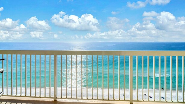 Un balcon avec vue sur une plage et l’océan.