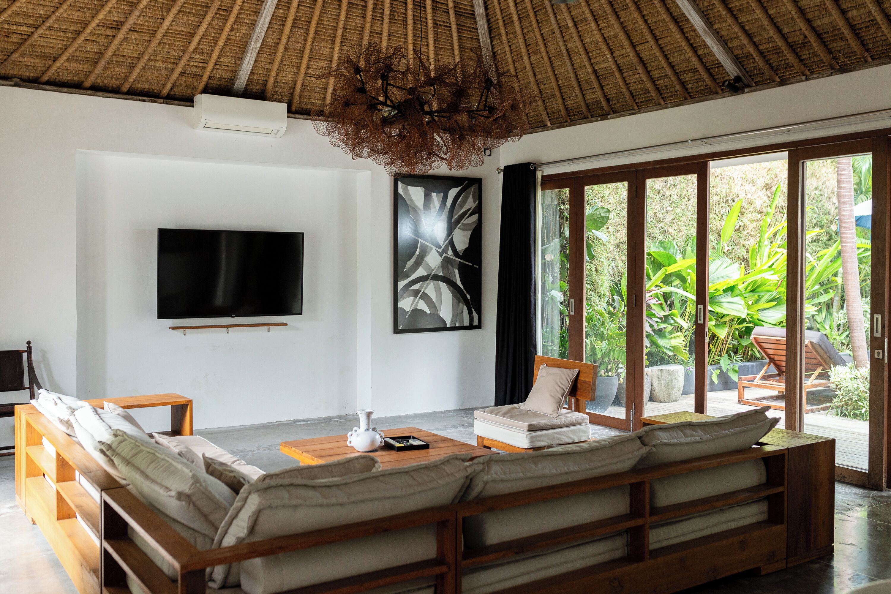 A modern living room with a large sofa, a flat-screen TV, and a dining table.