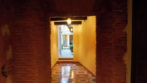 A corridor with patterned tiles, brick walls, and a hanging light fixture. - Casa Flavia @ Domus Santa Barbara Apartment with pool access in Zona Colonial (Santo Domingo)