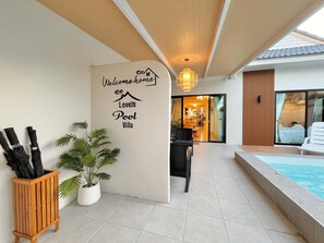 A villa with a pool, a welcome sign, and a dining area visible through the glass doors. - New Love Is Pool Villa, Modern 3BR Pool Villa Cozy Style (Surat Thani)