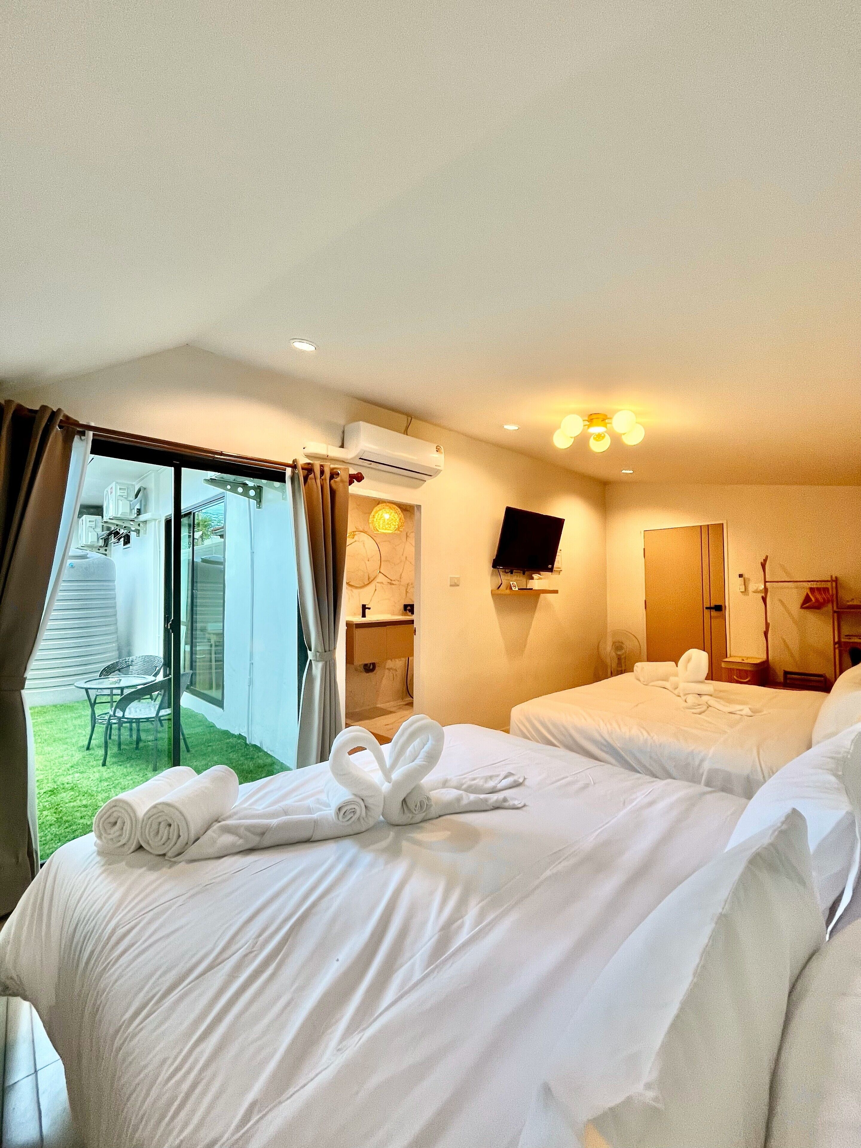 A hotel room with two beds, a TV, and a balcony with a table and chairs. - New Love Is Pool Villa, Modern 3BR Pool Villa Cozy Style (Surat Thani)
