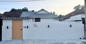 A residential building with a white exterior, a brown door, and a small window. A sign on the wall reads "Home 23/244". - New Love Is Pool Villa, Modern 3BR Pool Villa Cozy Style (Surat Thani)