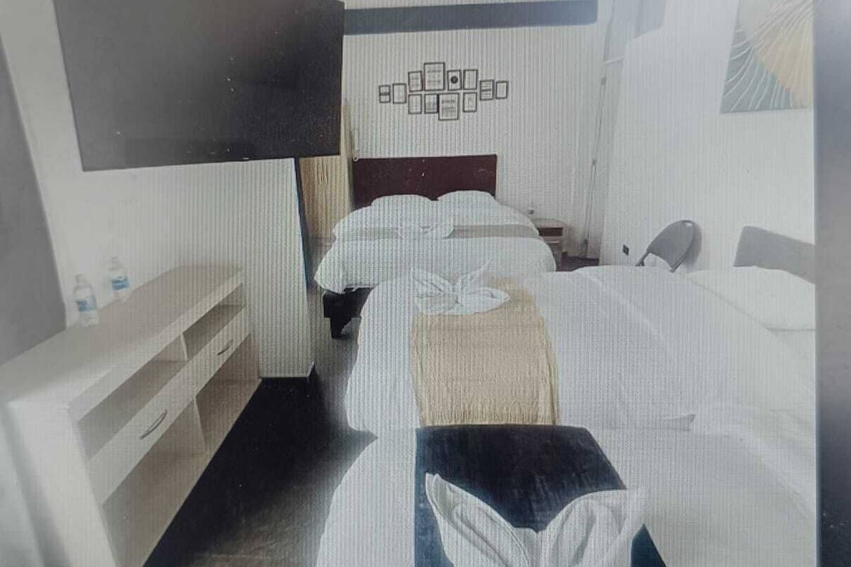 A hotel room with two beds, a desk, and a large mirror. There are framed pictures on the wall above the beds.
