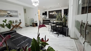 A modern living room with a black leather sofa, a dining area with a glass table, and a kitchen with stainless steel appliances. - Hotel Oti (Cajamarca)