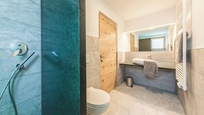 Een moderne badkamer met douche, toilet en wastafel.